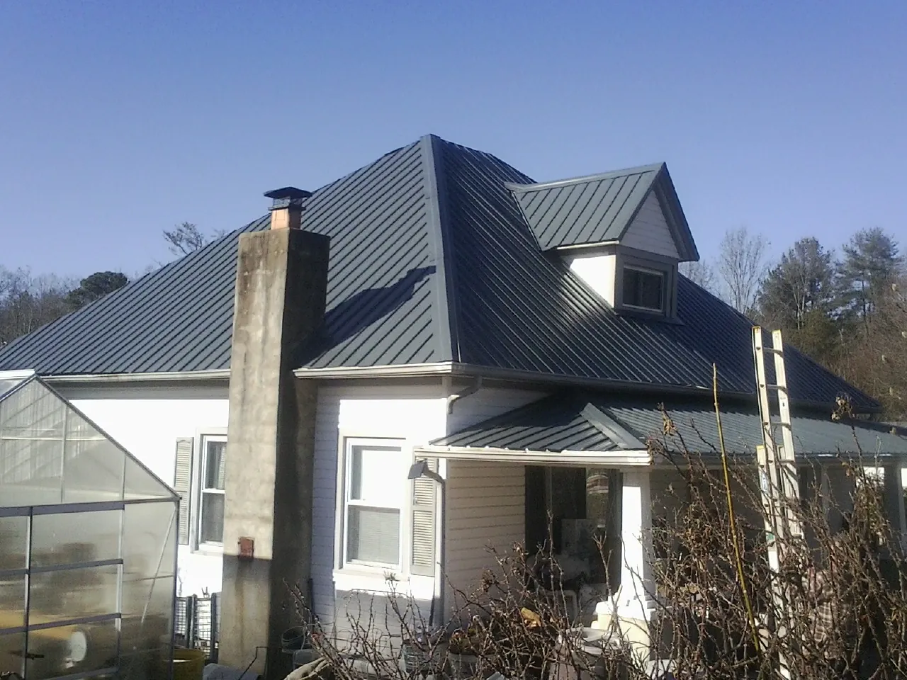 Dark blue standing seam metal roof on a white farmhouse with dormer — Slate & Tile Roof Repair by Roofing Brothers in Hawaiian Gardens