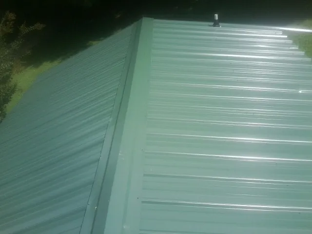 New green metal panels meeting at the ridge of a roof — Flat Roof Repair work by our crew in Hawaiian Gardens