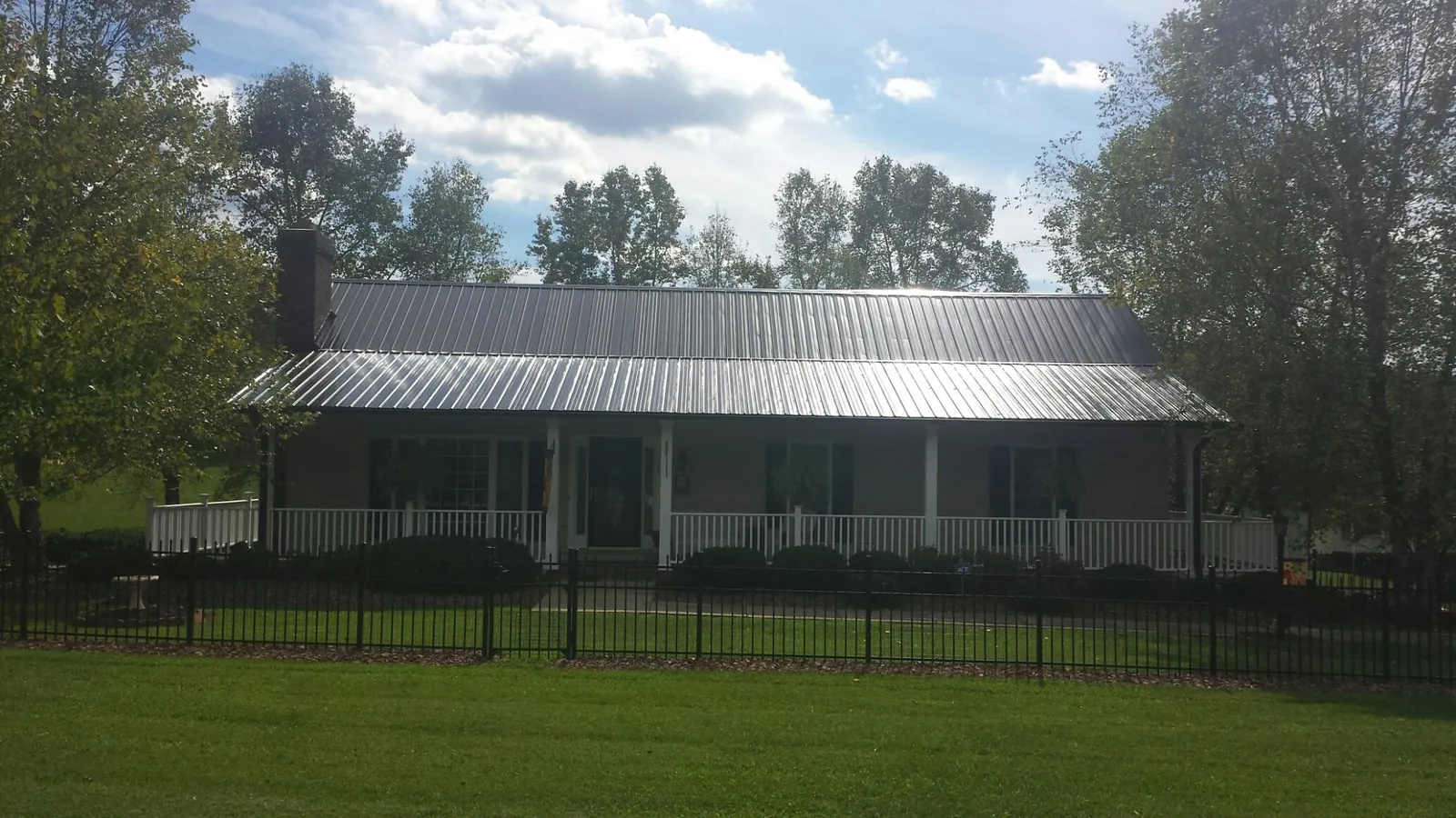 Gray metal roof on a brick ranch with a full width front porch — Gutter Guard Installation work by our crew in Hawaiian Gardens