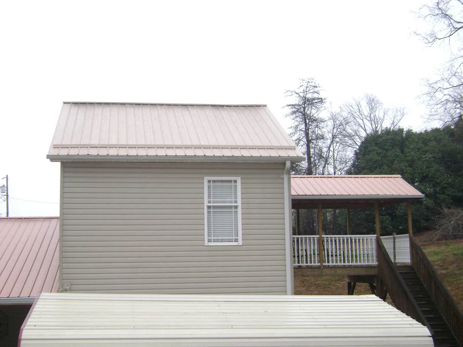 Tan metal roofs on a two story addition and attached porch, from a Roof Replacement job in Hawaiian Gardens